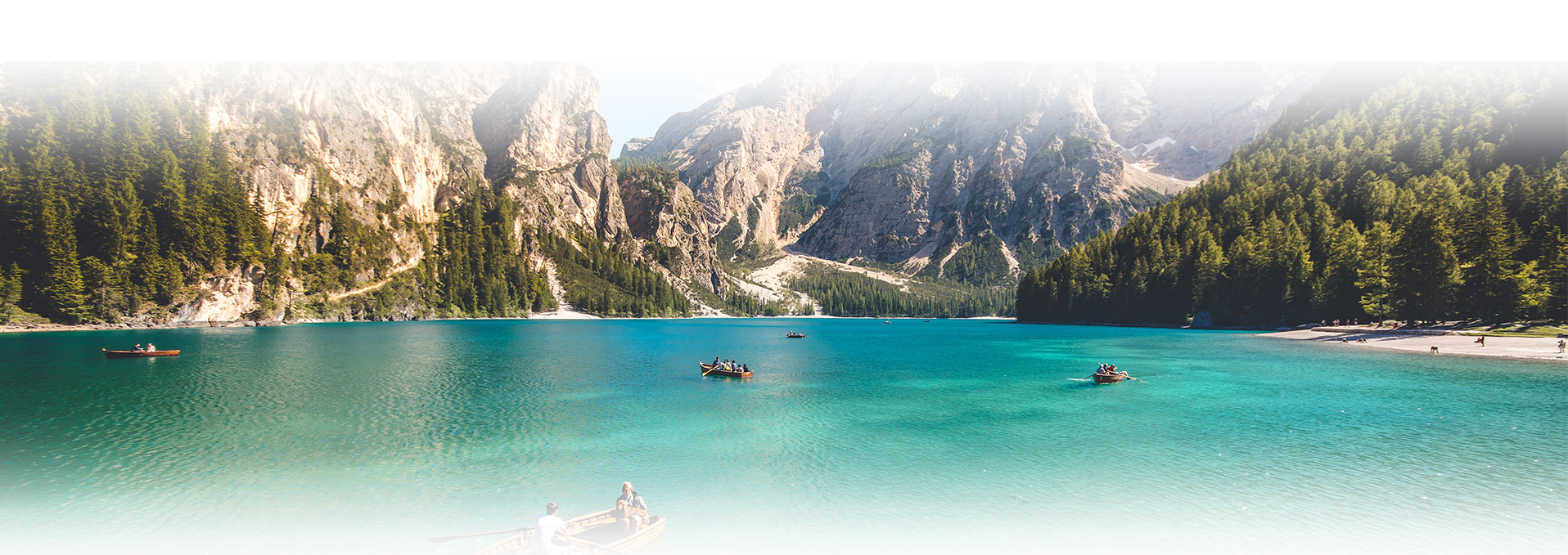 Turquoise alpine lake with boats and mountains
