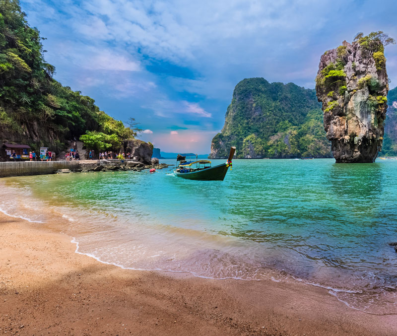Tropical beach with longtail boat and limestone karsts